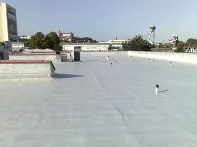 Plochá strecha so svetlou fóliou, v pozadí panoráma mesta